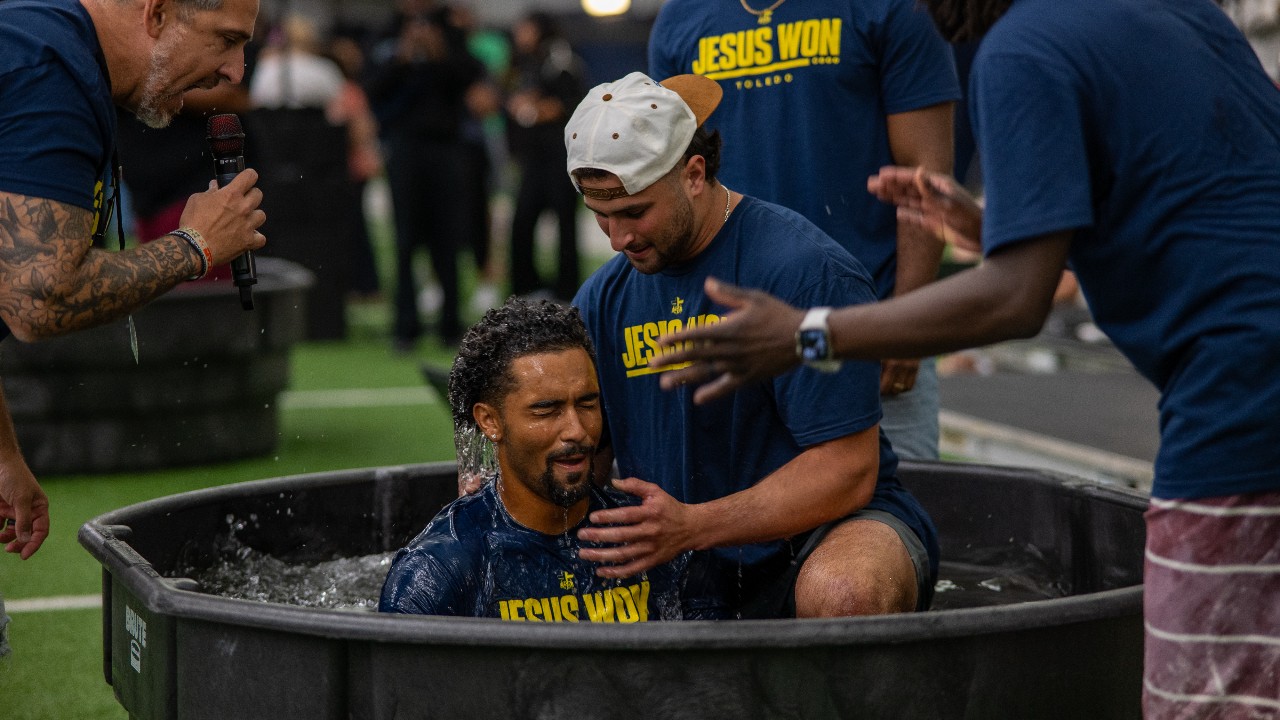 Ben Sahakian baptizes a man in a tub on the turf at Fetterman Training Center