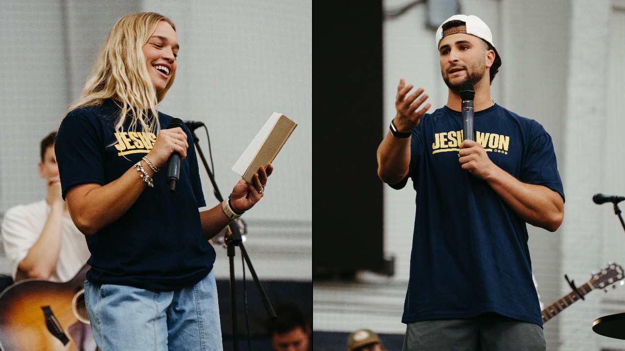 Janelle Green holds a Bible and a microphone beside Ben Sahakian speaking at UToledo Baptism Night